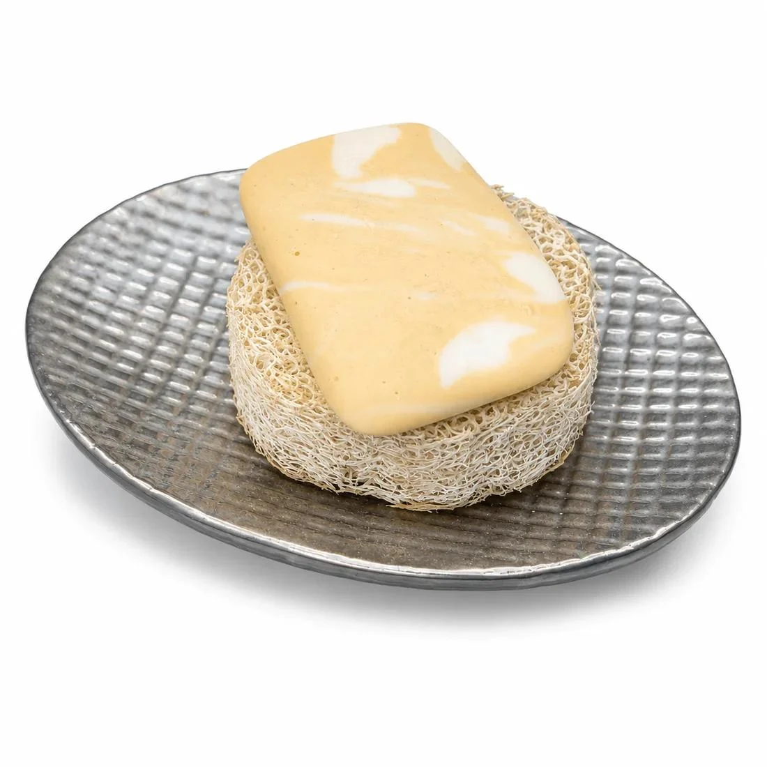 Ein Stück Seife auf einer Luffa-Scheibe in einer silberfarbenen Schale